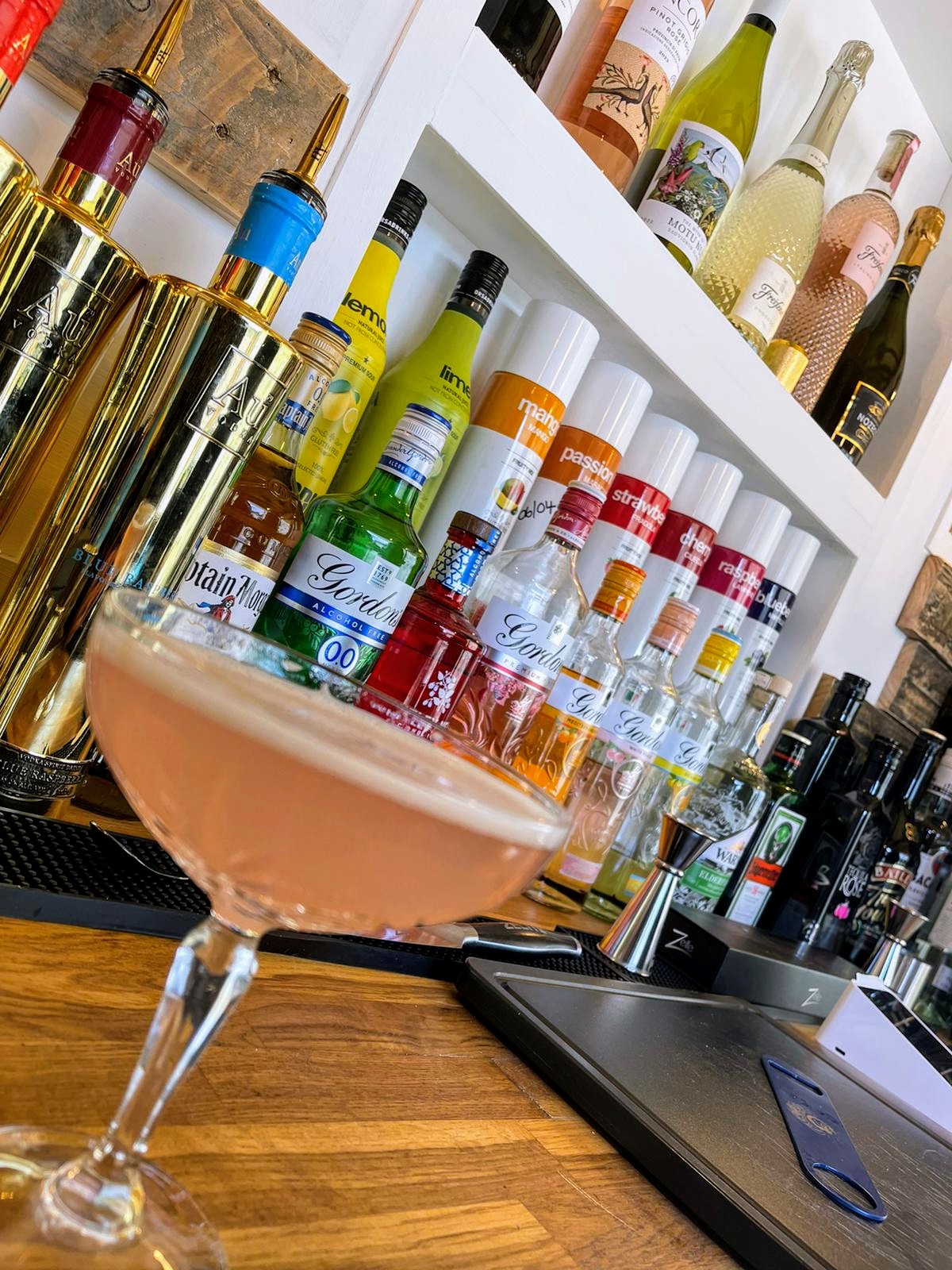 A cocktail served at The White Oak bar with spirits and mixers behind